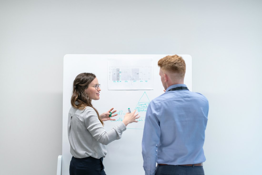 Profissionais discutindo um diagrama no quadro branco